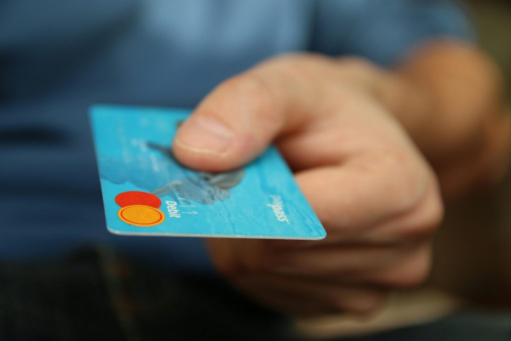 money-card-business-credit-card-50987-50987 A close-up shot of a hand offering a blue debit card for payment.